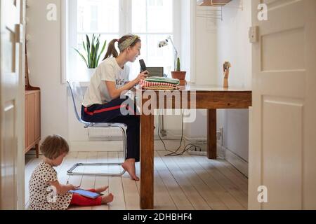Podcaster talking on microphone while daughter using digital tablet at home Stock Photo