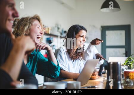 Confident cheerful IT professionals sitting at table while working in creative office Stock Photo