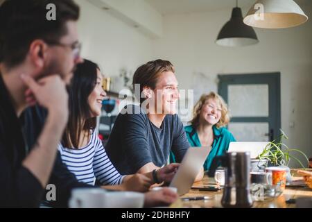 Happy computer programmers looking away while working at table in office Stock Photo