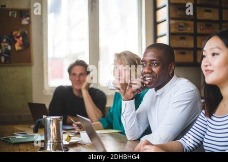 Confident young IT experts looking away while sitting at desk in creative workplace Stock Photo
