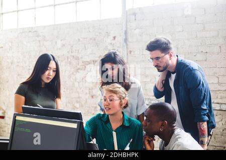 Young female entrepreneur having discussion over computer codes with hackers in office Stock Photo