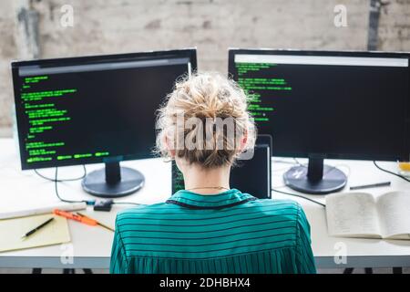 High angle view of female IT expert working on computer programs at desk in creative office Stock Photo
