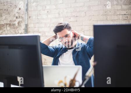 Serious young computer programmer looking at laptop while working in office Stock Photo