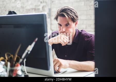 Worried professional hacker looking at laptop in creative office Stock Photo