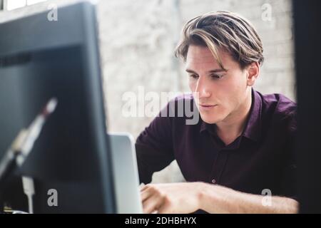 Male computer programmer using laptop while working in office Stock Photo