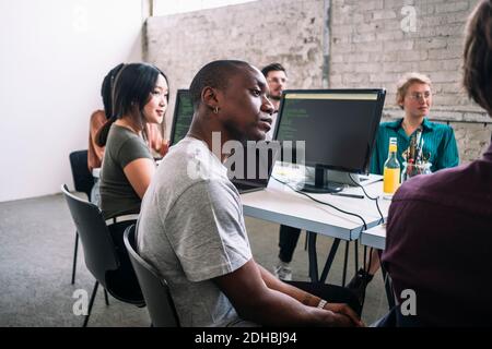 Confident male and female IT professionals sitting in board room during meeting at creative workplace Stock Photo