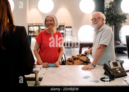 Smiling senior couple talking to receptionist in hotel Stock Photo