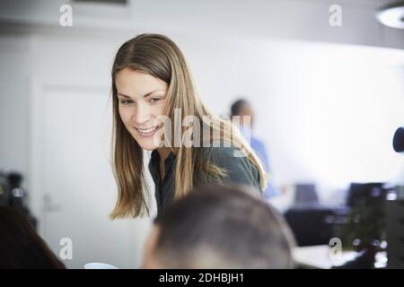 Smiling businesswoman looking at coworker in office Stock Photo