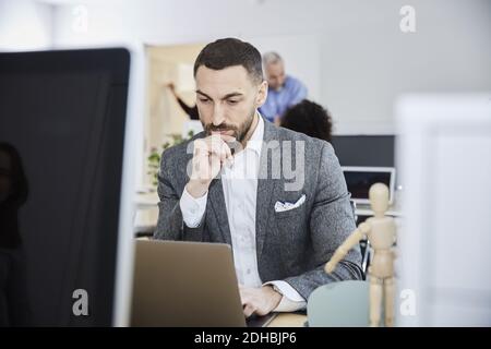 Serious businessman using laptop at desk in office Stock Photo