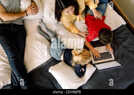 High angle view of mother and girl with boy using laptop on bed Stock Photo