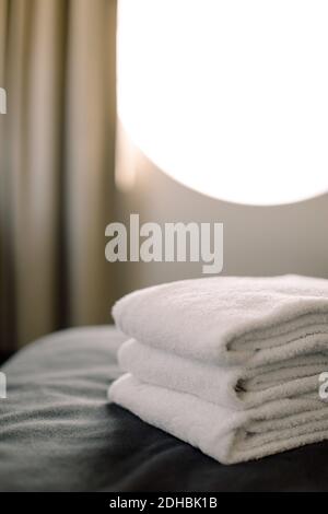 Close-up of stacked towels on bed in hotel Stock Photo