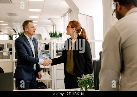 Businesswoman shaking hand with sales manager in office Stock Photo