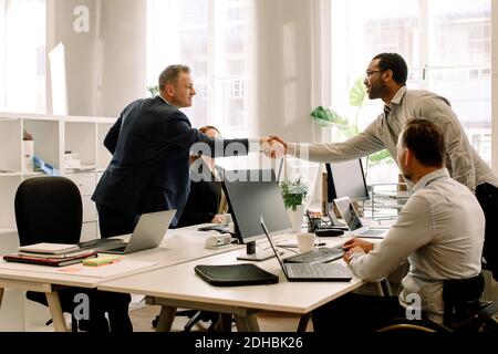 Businessmen shaking hands during sales meeting in office Stock Photo