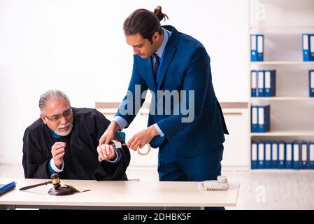 Police inspector arresting old judge in court Stock Photo