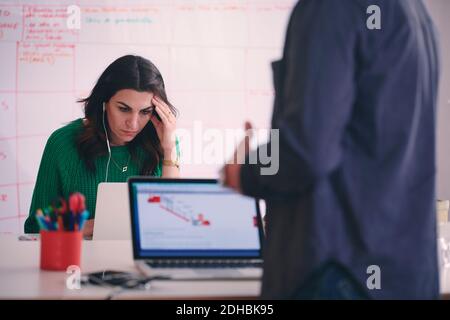 Tensed creative businesswoman using laptop at desk in office Stock Photo