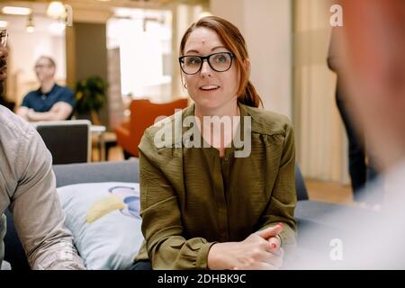 Confident businesswoman wearing eyeglasses while sitting in office Stock Photo