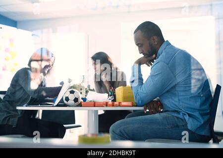 Male engineer thinking while colleagues working at table in office Stock Photo