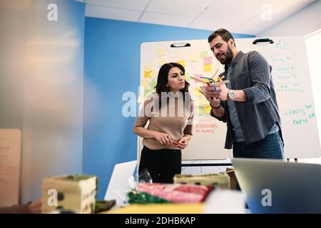 Male and female engineers discussing over project at table in office Stock Photo