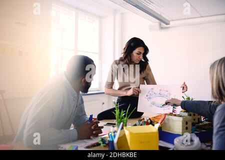 Male and female engineers discussing over diagram at table during meeting in office Stock Photo