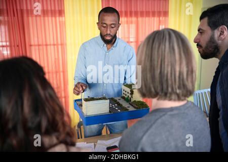 Male engineer explaining colleagues over architectural model during meeting in office Stock Photo