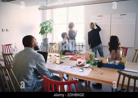 Female engineer explaining colleagues over whiteboard during meeting in office Stock Photo