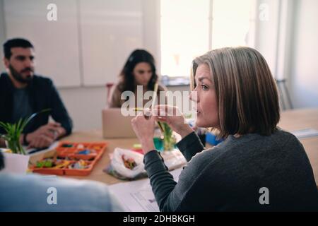 Female engineer looking away while working on project with colleagues at table in office Stock Photo