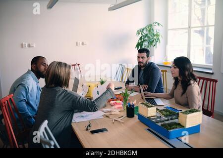 Male and female engineers sharing ideas while working on project at table in office Stock Photo