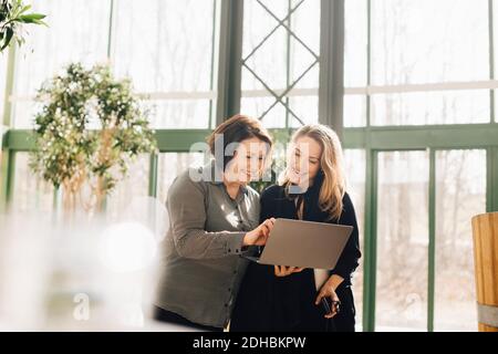 Happy business colleagues discussing over laptop at office Stock Photo