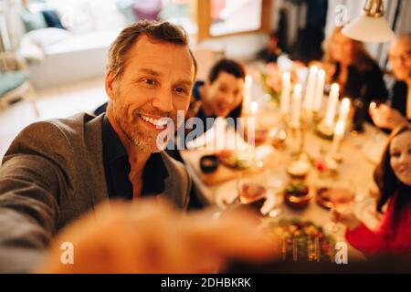 Mature man taking selfie with friends at dinner party Stock Photo