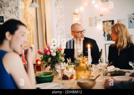 Mature friends talking while enjoying food at dinner party Stock Photo