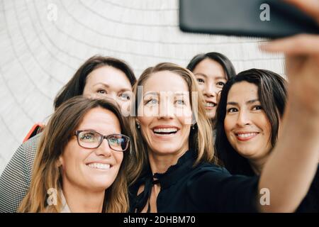 Smiling businesswoman taking selfie with female professionals at office during conference event Stock Photo