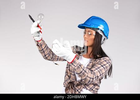 Serious female electrician repairing light with a light bulb in her hands. White background. Stock Photo