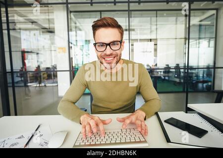 Young man in glasses using computer keyboard and posing Stock Photo