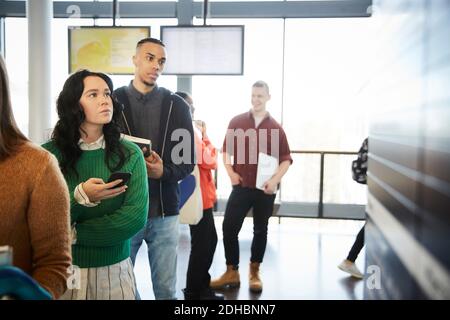 Male and female young bored students waiting in line at university Stock Photo