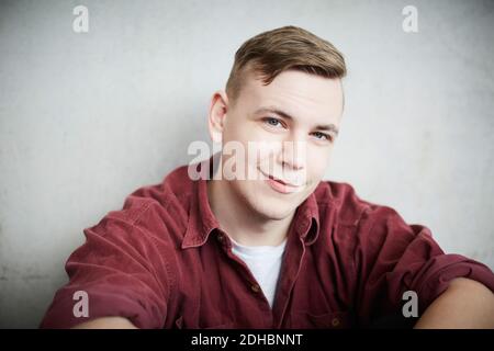 Close-up portrait of young male student against wall in university Stock Photo