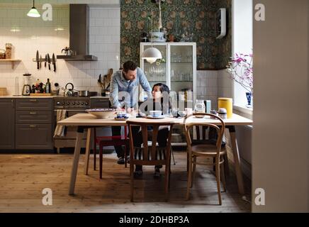 Father helping son in doing homework at home Stock Photo