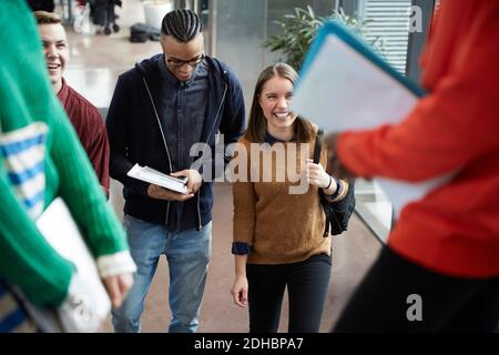 Friends talking to female students standing in university Stock Photo