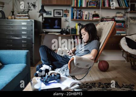 Boy using smart phone while sitting in living room at home Stock Photo