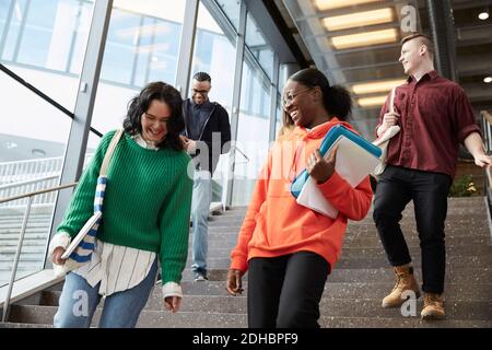 Low angle view of happy university students walking down on steps Stock Photo