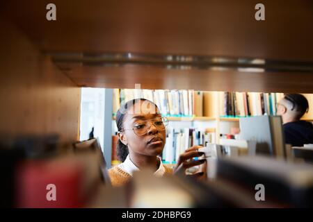 Male and female university students reading books in library Stock Photo