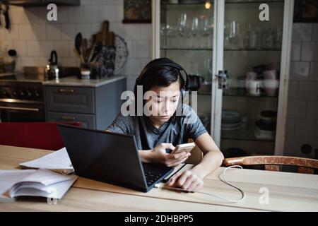 Boy using mobile phone for homework at home Stock Photo