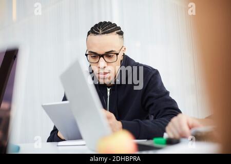 Young student using digital tablet while studying at table in university cafeteria Stock Photo