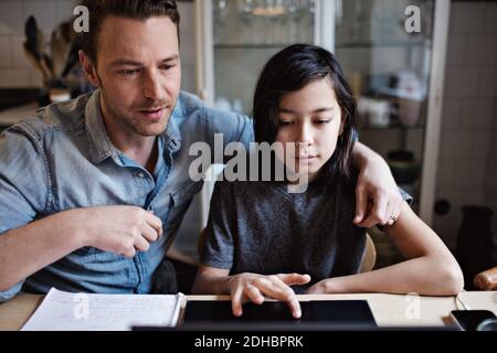 Son using laptop by father while doing homework at home Stock Photo