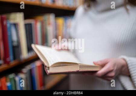 Young woman holding old book in the library Stock Photo