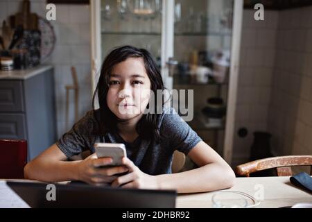 Portrait of smiling boy using mobile phone for homework at home Stock Photo