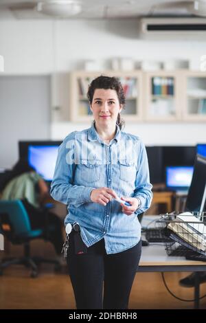 Portrait of confident mature female teacher standing in computer lab at high school Stock Photo