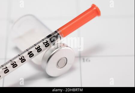 syringe with orange cannula and transparent vaccine vial with aluminum closure, PCR vial with cap, calendar envelope Stock Photo