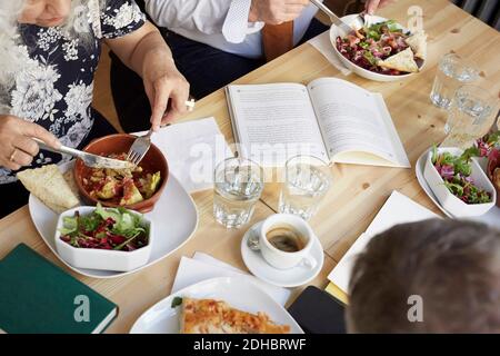 High angle view of friends having food at table in book club Stock Photo