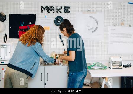 Female business colleagues working over cabinet in creative office Stock Photo