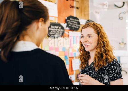 Smiling businesswoman discussing with female colleagues at creative office Stock Photo